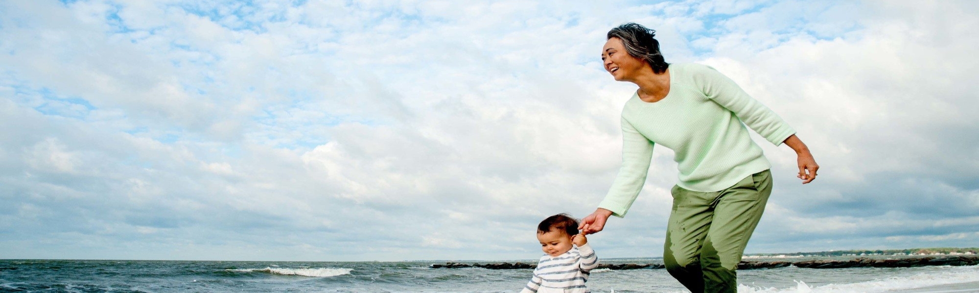 Woman walking on the beach with a toddler